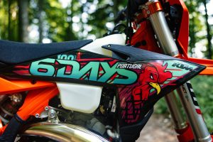 KTM 300 EXC 6DAYS 2027 – Detailansicht der seitlichen 6DAYS-100-Portugal-Grafik mit Barcelos-Hahn-Motiv und Sitzbank