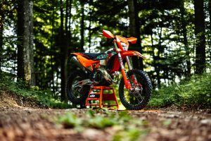 KTM 300 EXC 6DAYS 2027 – Enduro auf Montageständer auf einer Waldkuppe im Gegenlicht