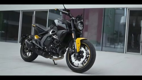 Letbe Arthur 700 2026 – Naked Bike in Schwarz-Gelb, Dreiviertelansicht von rechts vorne vor modernem Glasgebaeude