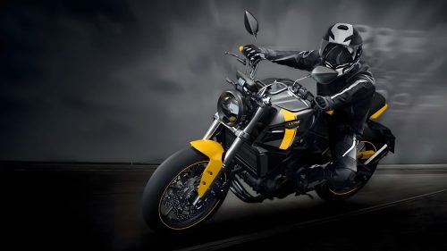 Letbe Arthur LB 700 2023 – dynamische Fahraufnahme mit Fahrer bei dramatischem Himmel, aelteres Retro-Design in Schwarz-Gelb