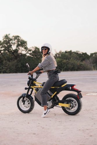 LiveWire S4 Honcho Street 2026 in Gelb – Fahrerin sitzt seitlich auf dem Minibike in einem Feld bei Sonnenuntergang