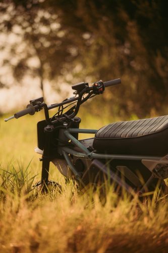 LiveWire S4 Honcho Trail 2026 – Detailaufnahme: Hände am Lenker, Tarnmuster-Nummernschild und LiveWire-Akkukasten im Gras