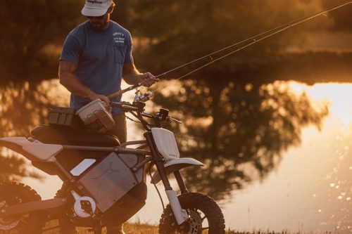 LiveWire S4 Honcho Trail 2026 in Weiß – Mann angelt neben dem mit Kühlbox und Angelkoffer beladenen Minibike am See bei Sonnenuntergang