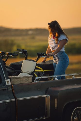 LiveWire S4 Honcho Street 2026 – Frau verlädt die Minibikes auf einen Oldtimer-Pick-up bei Sonnenuntergang