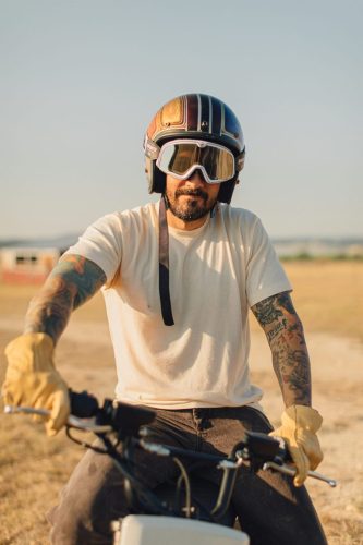 LiveWire S4 Honcho 2026 – Porträt eines Fahrers mit Jethelm, Schutzbrille und Lederhandschuhen auf dem Minibike in einem Feld