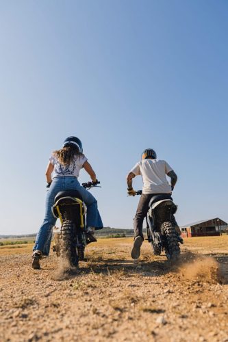 LiveWire S4 Honcho Trail 2026 – Heckansicht zweier Fahrer, die ihre Minibikes auf einem Schotterweg beschleunigen, mit Staubfahne