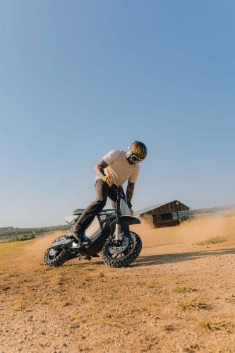 LiveWire S4 Honcho Trail 2026 in Grau – Fahrer beim Stunt mit angehobenem Vorderrad in einem staubigen Feld vor einer Scheune