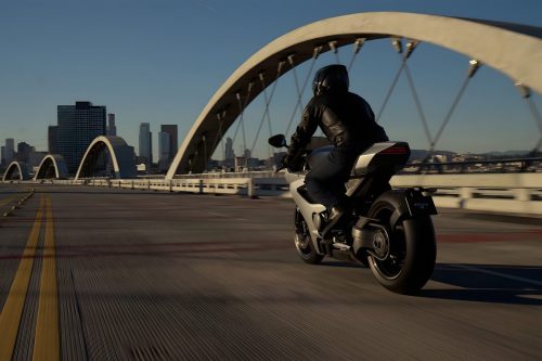 Norton Manx R Signature 2026 – Heckansicht in Fahrt auf Brücke mit LED-Rücklicht und Stadtsilhouette im Hintergrund