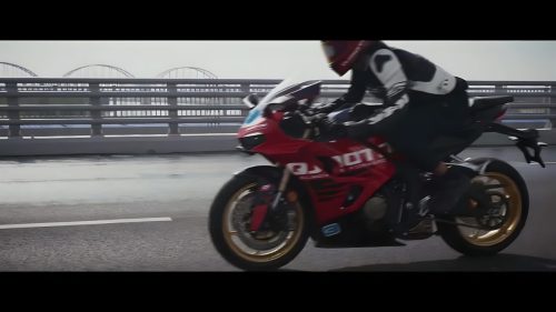 QJMotor SRK 800 RC 2026 – Actionfoto auf nasser Brücke bei Regen, Fahrer in Rennkombi, rote Vollverkleidung mit goldenen Rädern, cinematischer Widescreen-Look