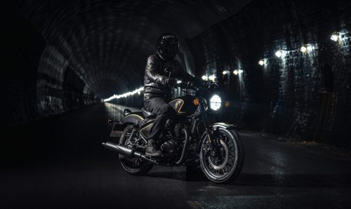Royal Enfield Shotgun 650 x Rough Crafts – Fahrer in schwarzer Lederkombi im beleuchteten Tunnel, Frontansicht mit eingeschaltetem Scheinwerfer