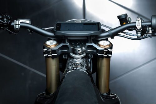 Stark VARG SM Sköll 2026 – Nahaufnahme von Cockpit und goldener Gabel von oben, Metallwand im Hintergrund