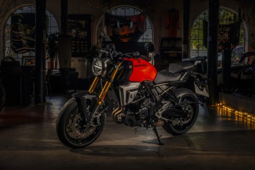 Suzuki GSX-8T 2027 in Glass Blaze Orange in einer dunklen Werkstatt-Location mit Kerzenlicht