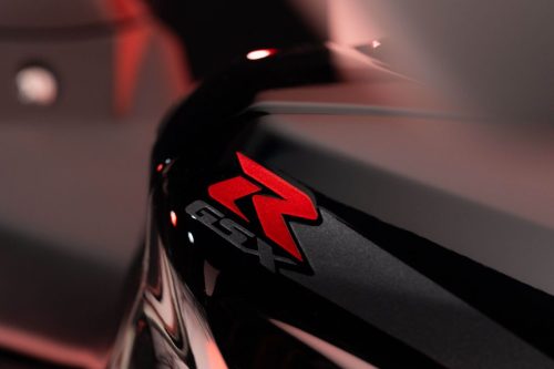 Suzuki GSX-R1000R Stealth – Nahaufnahme des roten GSX-R-Logos in stimmungsvollem rotem Studiolicht