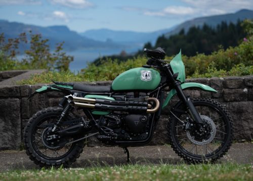 Triumph Scrambler 1200 Custom-Umbau aus den USA – Enduro in Mintgrün mit UAK-Tankemblem vor Bergpanorama mit See