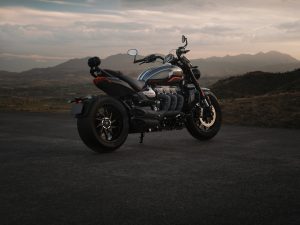 Triumph Rocket 3 Storm GT 2027 – Dreiviertel-Heckansicht an einem Bergaussichtspunkt in der Dämmerung