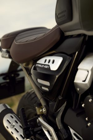 Triumph Scrambler 400 X 2027 – Detailansicht von Sitzbank und Seitendeckel mit Scrambler-400-Schriftzug