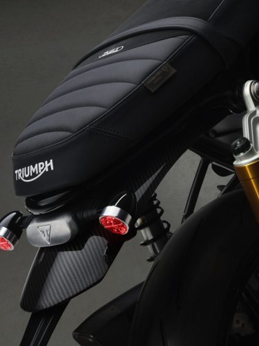 Triumph Speed Twin 1200 TFC 2027 – Detail der Sitzbank aus echtem Leder und Wildleder mit Triumph-Stickerei, Genuine-100-Leather-Label und Carbon-Heckabdeckung