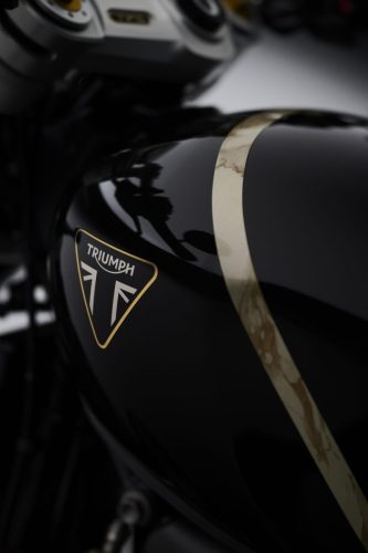Triumph Speed Twin 1200 TFC 2027 – Nahaufnahme des Triumph-Tankemblems mit goldenem Blattgold-Zierstreifen auf Obsidian-Gold-Lack