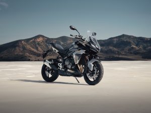 Triumph Tiger Sport 800 2027 – Dreiviertel-Heckansicht auf weiter Ebene vor Bergen