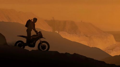 Ultraviolette Shockwave – Fahrer mit Shockwave als Silhouette auf Berggrat bei Sonnenuntergang, dramatische Offroad-Szene mit orangefarbenem Himmel