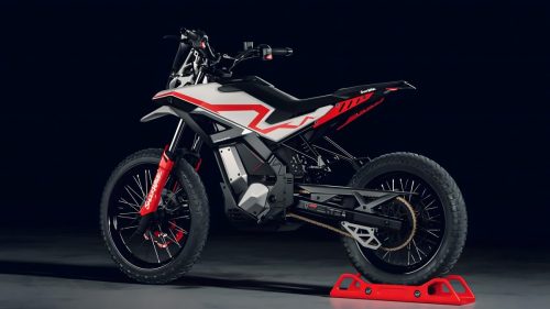 Ultraviolette Shockwave – Dreiviertelansicht von vorne links in Frost White mit roter Telegabel, Doppelsitz-Option, sichtbarem Batterie- und Motorbereich auf rotem Montageständer