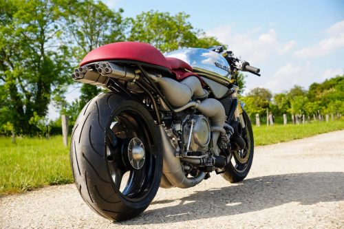 Veloce Aperion 2026 – Rechte Heckansicht im Freien mit poliertem Aluminiumtank, rotem Sitz, Gitterrohr-Schwinge und Expansionskammern vor Weinberg-Landschaft