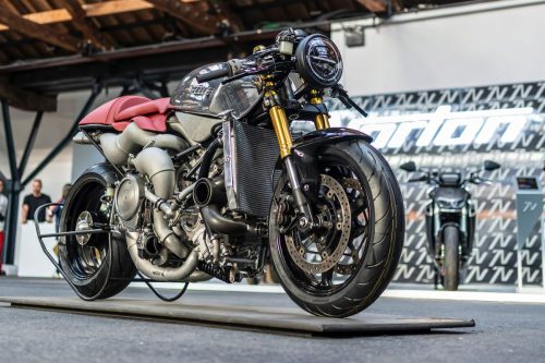 Veloce Aperion 2026 – Rechte Dreiviertelansicht von vorn auf Motorradmesse mit Kühler, goldenen Gabeln und rundem Scheinwerfer, Norton-Stand im Hintergrund