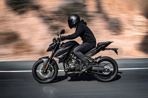 Voge R125S 2026 – Actionfoto in Fahrt auf Landstraße vor Felswand, Fahrer in schwarzer Kleidung, Bewegungsunschärfe im Hintergrund