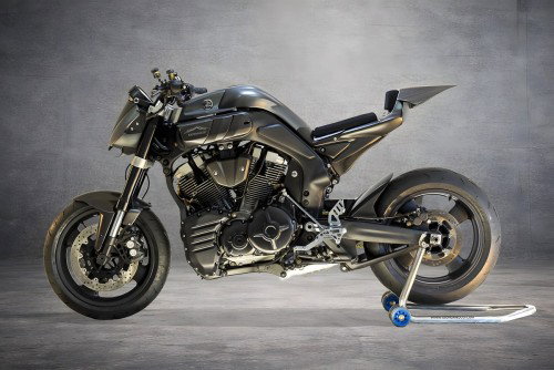 Yamaha MT-01 ORCO – Seitenansicht rechts auf Metallgitter, skulpturale Karbonfaser-Karosserie mit mattgrauem Finish, freiliegender V-Twin-Motor