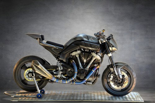 Yamaha MT-01 ORCO – Seitenansicht links im Studio, vollständige Karbonfaser-Karosserie, goldene Titan-Auspuffanlage, goldene Kette, blauer Montageständer auf Metallgitter