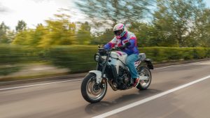 Yamaha XSR900 2027 – Fahraufnahme in Neon White auf einer Landstraße mit Bäumen und Hecken im Hintergrund