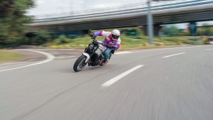 Yamaha XSR900 2027 – in Neon White in Schräglage in einer Kurve unter einer Autobahnbrücke