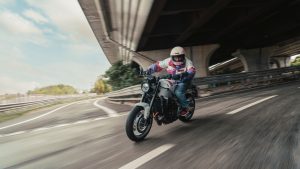 Yamaha XSR900 2027 – Fahraufnahme in Neon White in einer Kurve unter einer Hochstraße