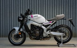 Yamaha XSR900 2027 – Seitenansicht in Neon White auf Montageständer vor einer Wellblechwand