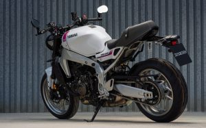 Yamaha XSR900 2027 – Heckansicht schräg in Neon White mit Kennzeichenhalter vor einer Wellblechwand