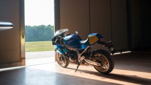 Yamaha XSR900 GP 2027 – schräge Heckansicht in Legend Blue im Hangar vor geöffnetem Tor