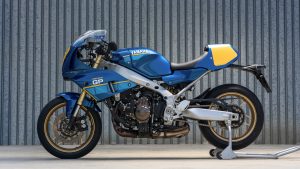 Yamaha XSR900 GP 2027 – Seitenansicht in Legend Blue auf Montageständer vor einer Wellblechwand