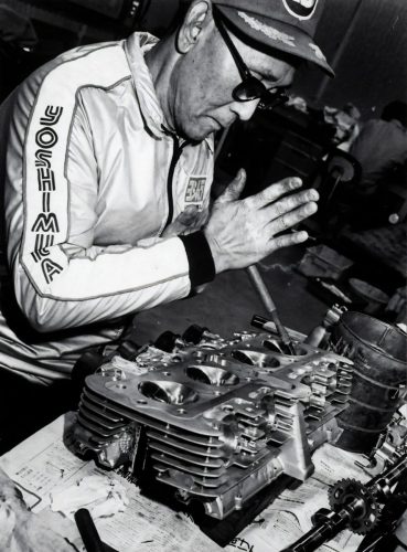 Historische Schwarzweißaufnahme: Hideo 'Pops' Yoshimura bei der Arbeit an einem Zylinderkopf in der Werkstatt (zeitgeschichtliches Pressefoto, Bildnachweis Yoshimura Japan)