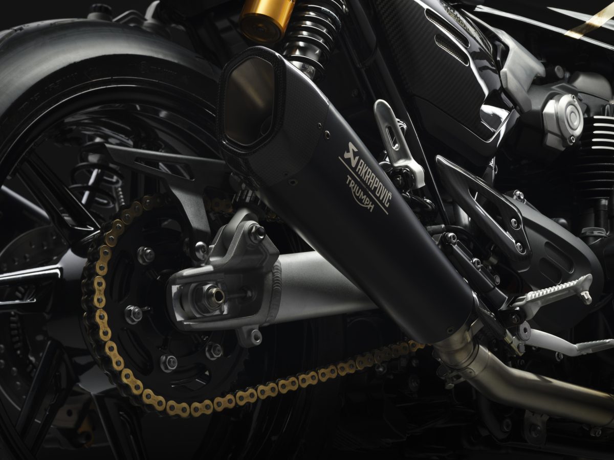 Triumph Speed Twin 1200 TFC 2027 – Detail des Akrapovič-Schalldämpfers mit goldener Kette, hinterem Kettenrad und Öhlins-Federbein